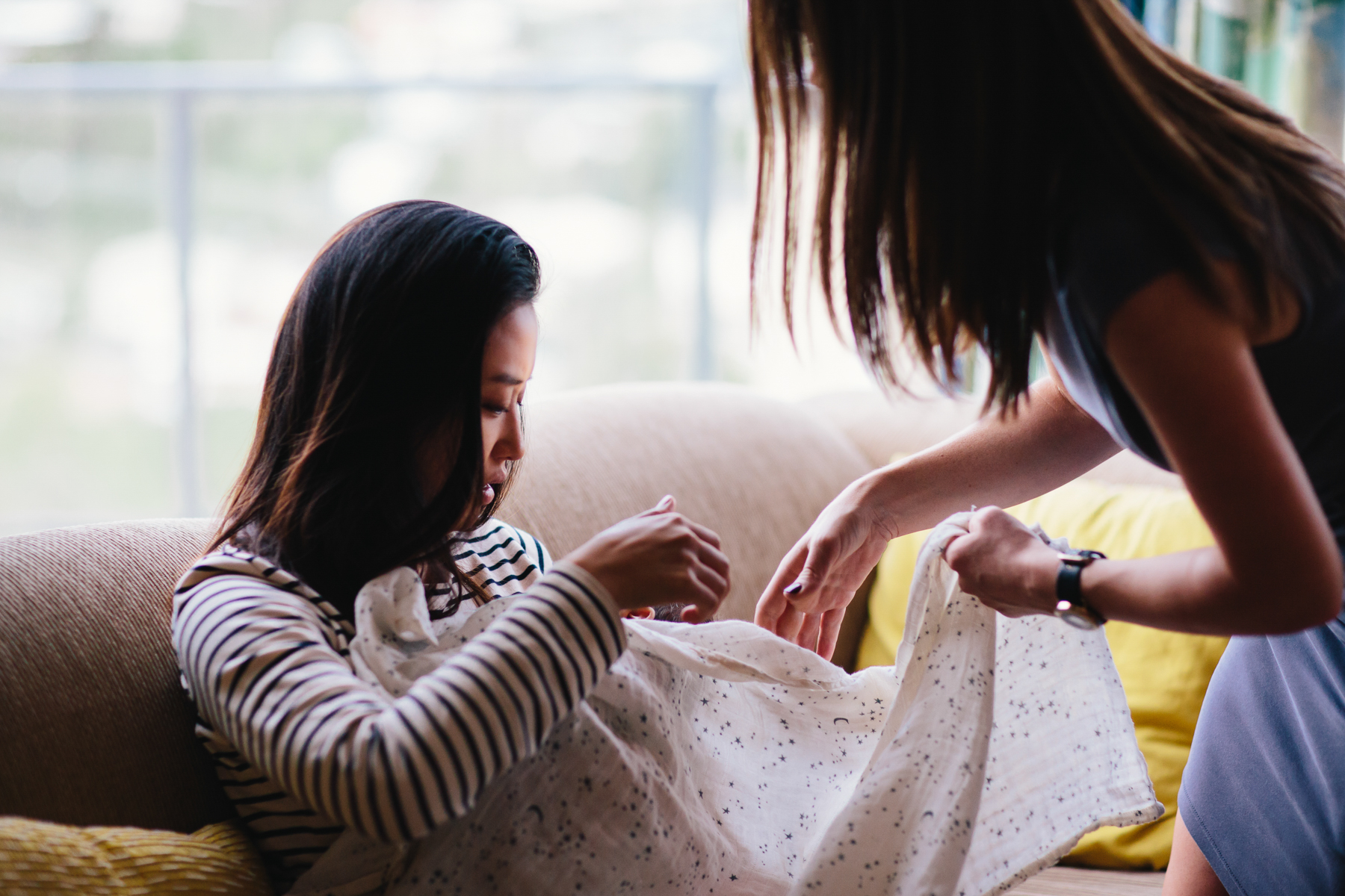 mom and aunt wrapping newborn baby in blanket Wellington in home family photography natural light