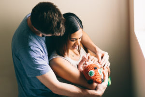 mom and dad holding baby girl with hat on Newborn Photography Wellington natural light